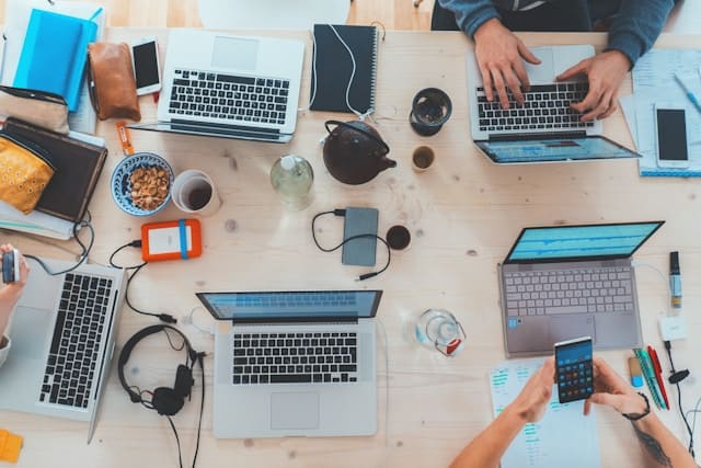 Multiple computers on a work table as students apply to college